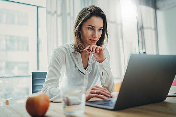 Mujer estudiando marketing digital frente a un computador