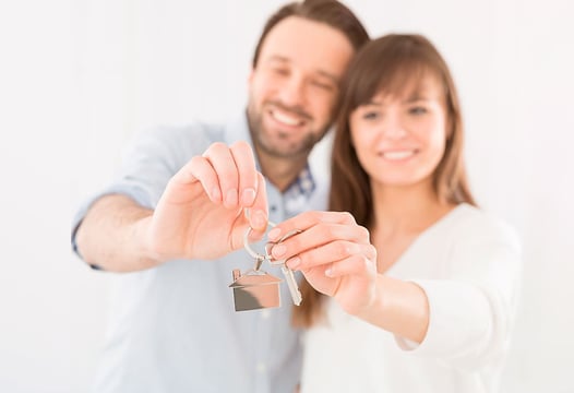 Una pareja sosteniendo en sus manos las llaves de su nueva casa.