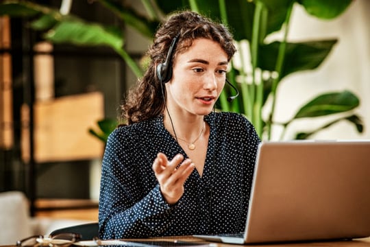 Una mujer frente a su computador portátil, brindando atención personalizada a usuarios Colsubsidio.