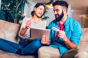 Una pareja feliz accediendo a los servicios de crédito Colsubsidio con su tarjeta multiservicios.