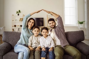 Familia en la sala de su casa, felices por adquirir su seguro de vida en Colsubsidio.