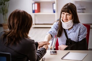 Una mujer con cuello ortopédico adquiriendo su seguro para accidentes personales.