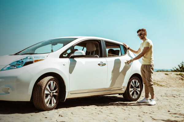 Hombre subiendo a su automóvil blanco en medio del desierto.