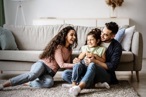 Padres con su hija divirtiéndose en la sala de su casa.