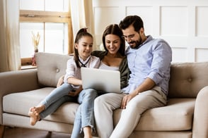 Familia con un computador portátil, revisando los servicios que brinda Colsubsidio.