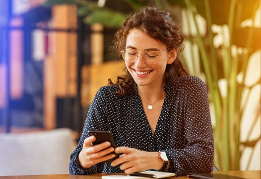 Mujer feliz navegando en internet por medio de su celular .