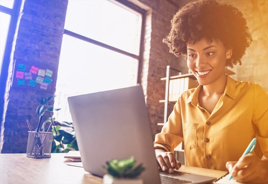Mujer afroamericana trabajando frente a su computador portátil.