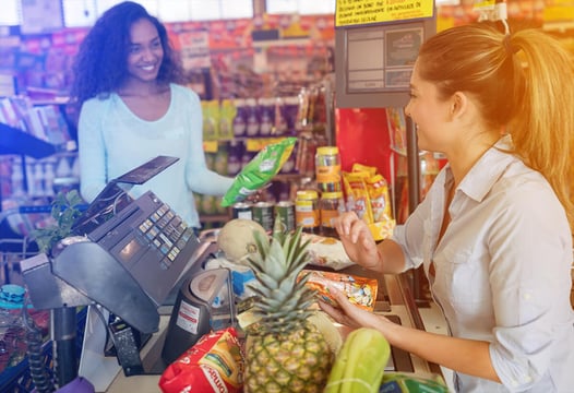 Mujer cajera atiendo a cliente de supermercados Colsubsidio.