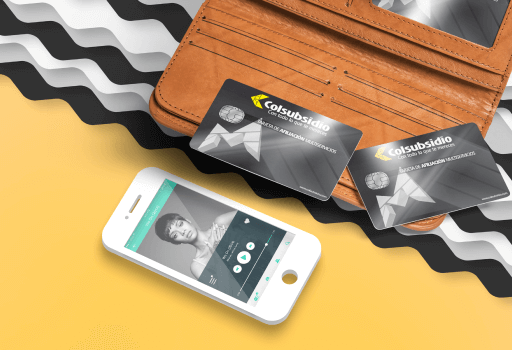 Un billetera con tarjetas Colsubsidio, a lado de un teléfono celular.