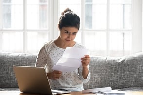 Mujer frente a su computador portátil, revisando sus cuentas.