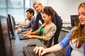 Un grupo de estudiantes en clases informáticas con su maestra.