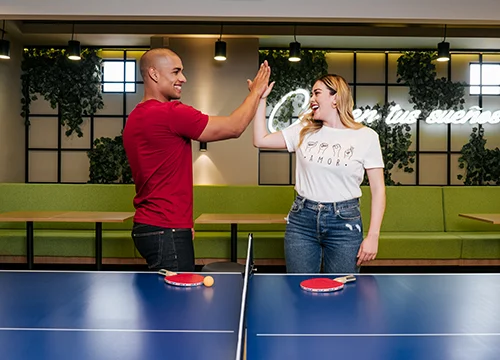 Dos personas chocando sus manos después de jugar tenis de mesa.