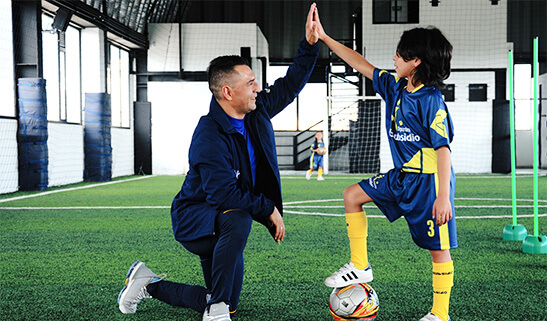 Niño y entrenador practicando fútbol