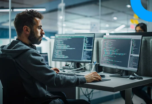 Un hombre al frente de su computador validando la ejecución de código de su empresa.