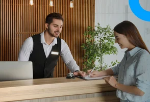 Un técnico en hotelería solicitando la firma de reserva de habitación a una huésped.