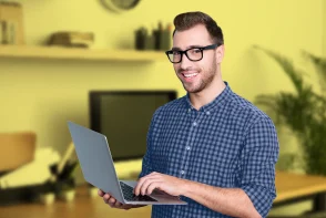 Un hombre con anteojos, estudiando los programas de CET en su computador portátil.