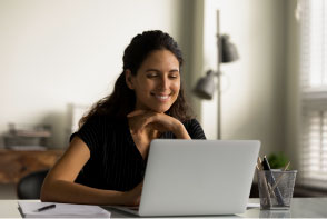 Mujer sonriente al frente de su portátil estudiando big data con power BI.
