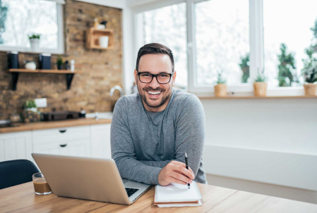 Hombre sonriendo trabajando en su computador portátil.