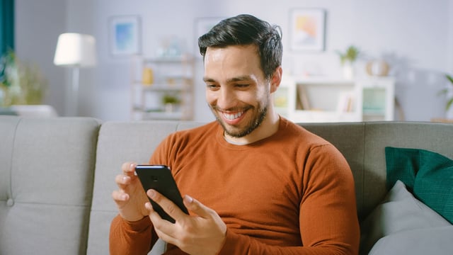 Hombre lee información del crédito hipotecario Colsubsidio, desde su teléfono celular.