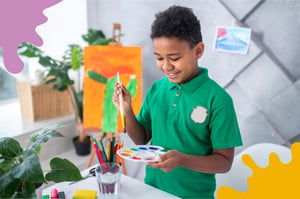 Un niño usando un pincel y una paleta de pinturas.