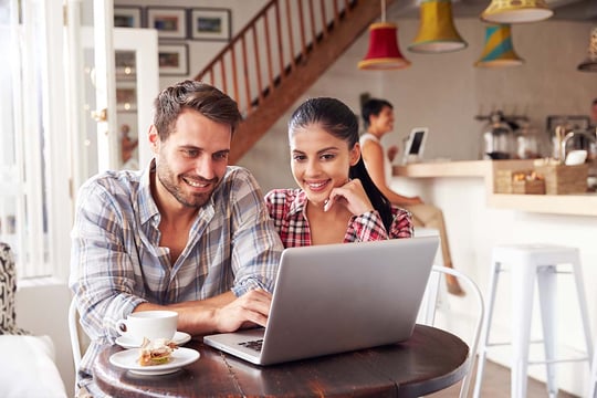 Una pareja en un café, revisando información sobre trámites para aportes.