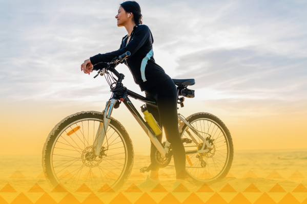 Una mujer con su bicicleta feliz de pertenecer a la comunidad de ciclistas de Colsubsidio. 