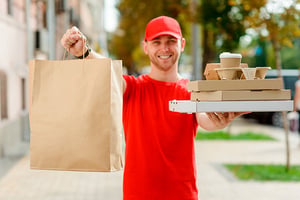 Hombre con bolsas y paquetes con comida, listo para hacer su entrega a domicilio.