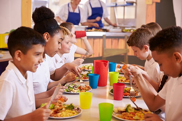 Niños y niñas comen en restaurante escolar.