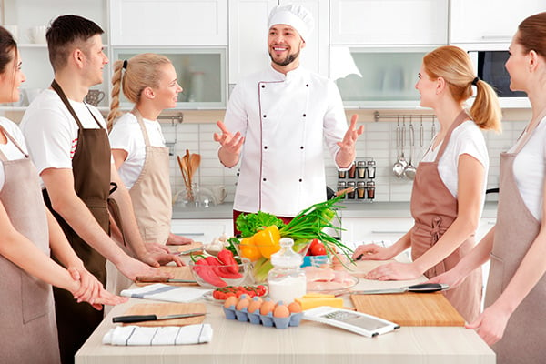 Cocinero habla a mujeres y hombres en la cocina.