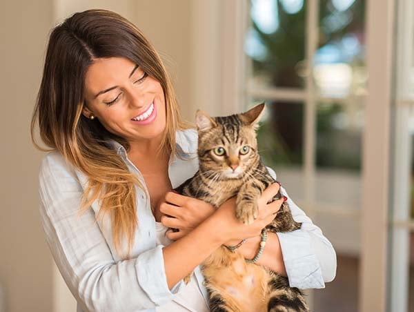 Una mujer sosteniendo a su gato, felices por acceder al seguro de mascotas Colsubsidio.