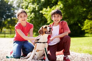 Un niño y una niña jugando con su perro en un parque.