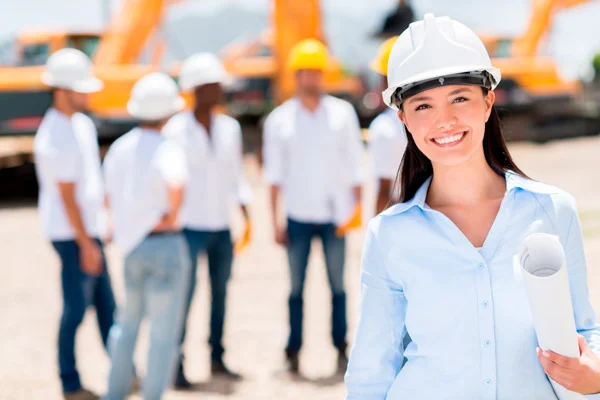 Mujer feliz con casco de construcción, al frente de sus compañeros de trabajo.