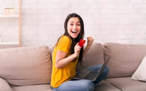 Mujer feliz sentada en un sofá, por su crédito de libre inversión Colsubsidio.