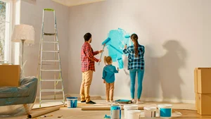 Dos padres y su hija, pintando una pared de su hogar.