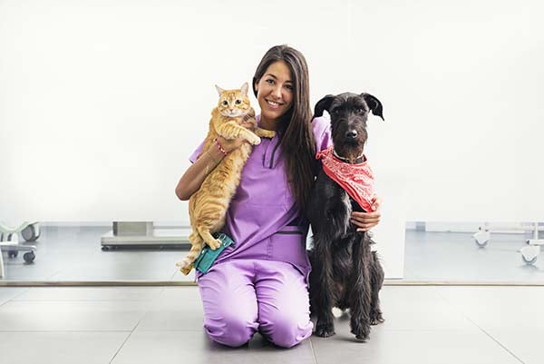 Una mujer veterinaria junto a un perro y un gato.