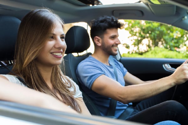 Una pareja viajando en su automóvil seguros con Sura.