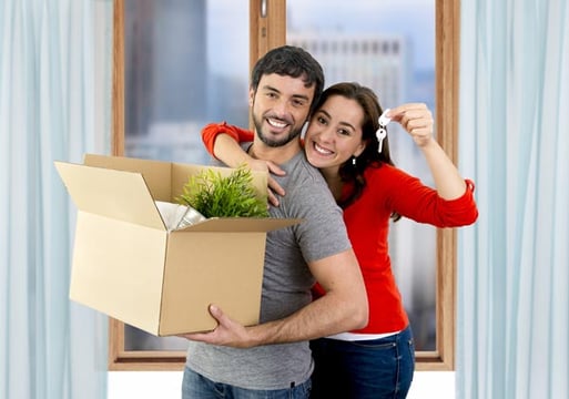 Una pareja feliz sosteniendo una caja y las llaves de su nuevo hogar.