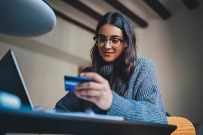 Mujer joven realizando compras online con su tarjeta de créditos.