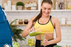 Una mujer con ropa deportiva, tomando un batido de proteína.