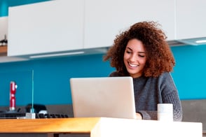 Una mujer frente a su computador portátil, trabajando en su oficina.