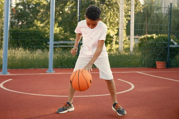 Niño juega baloncesto en escuela deportiva Colsubsidio.