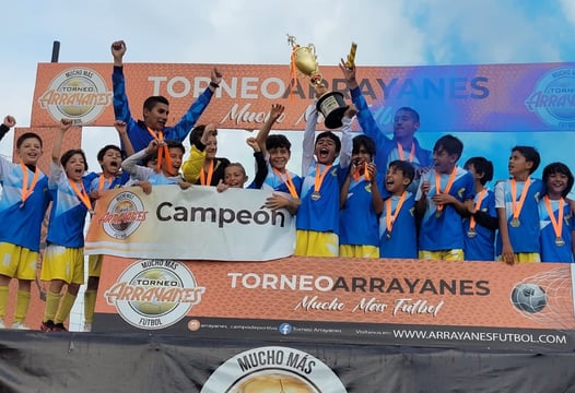 Equipo de niños de fútbol masculino alza trofeo de campeón.