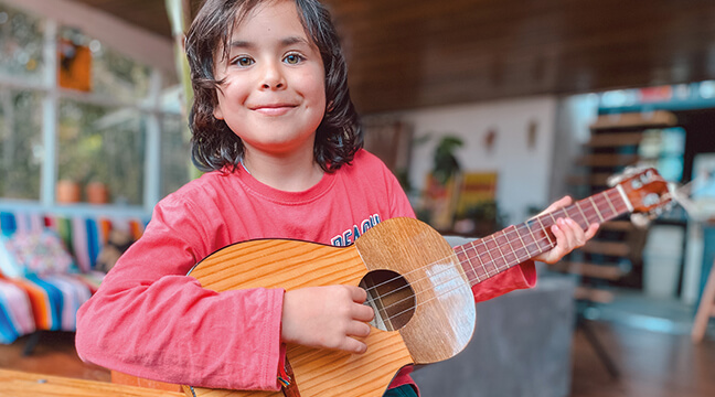Niña sonriendo y tocando la guitarra