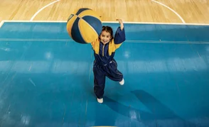 Niña alumna de colegios Colsubsidio, jugando con un balón de baloncesto.