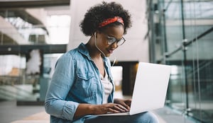 Una joven afroamericana, estudiando con ayuda de su computador portátil.