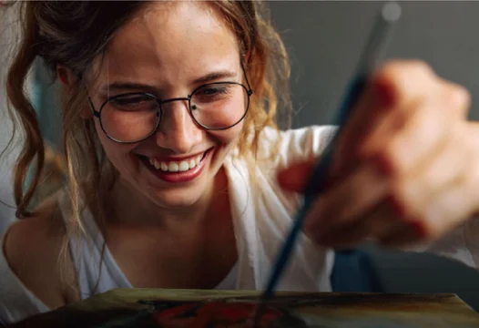Mujer con anteojos pintando un cuadro.