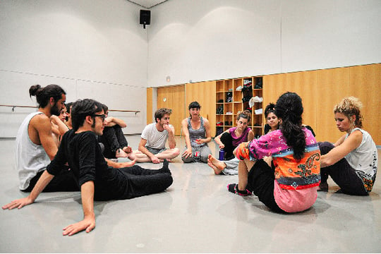 Varios estudiantes del programa de Teatro de Colsubsidio hablan mientras están sentados en el suelo del salón de ensayos.