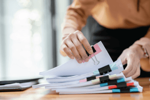 Una persona revisando documentos, en su sitio de trabajo.