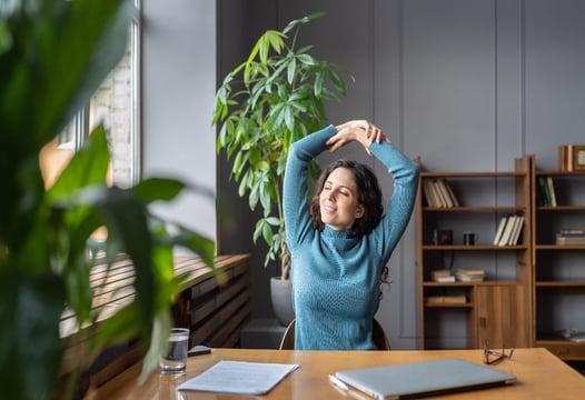 Una mujer realizando pausas activas en su sitio de trabajo.