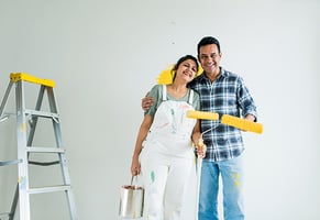 Una pareja pintando las paredes de su nuevo hogar.